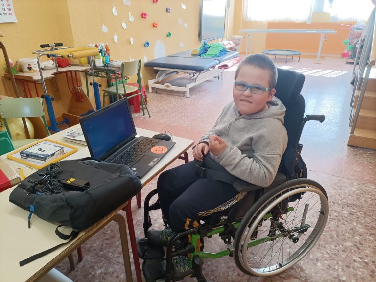 Un niño con parálisis cerebral utiliza un ordenador portátil en un aula de Aspace Madrid
