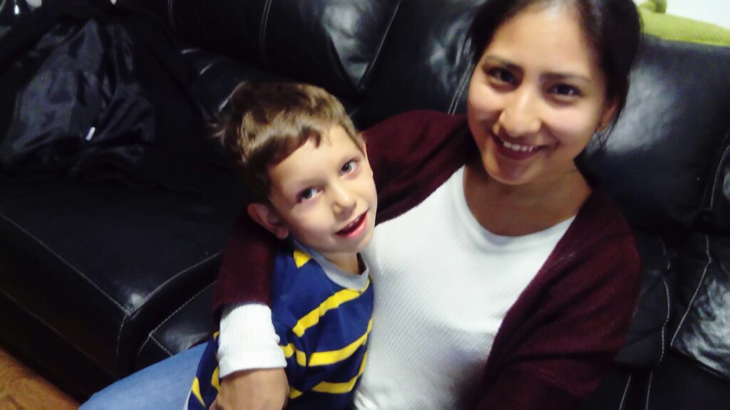 Una madre sostiene sonriente a su hijo con parálisis cerebral