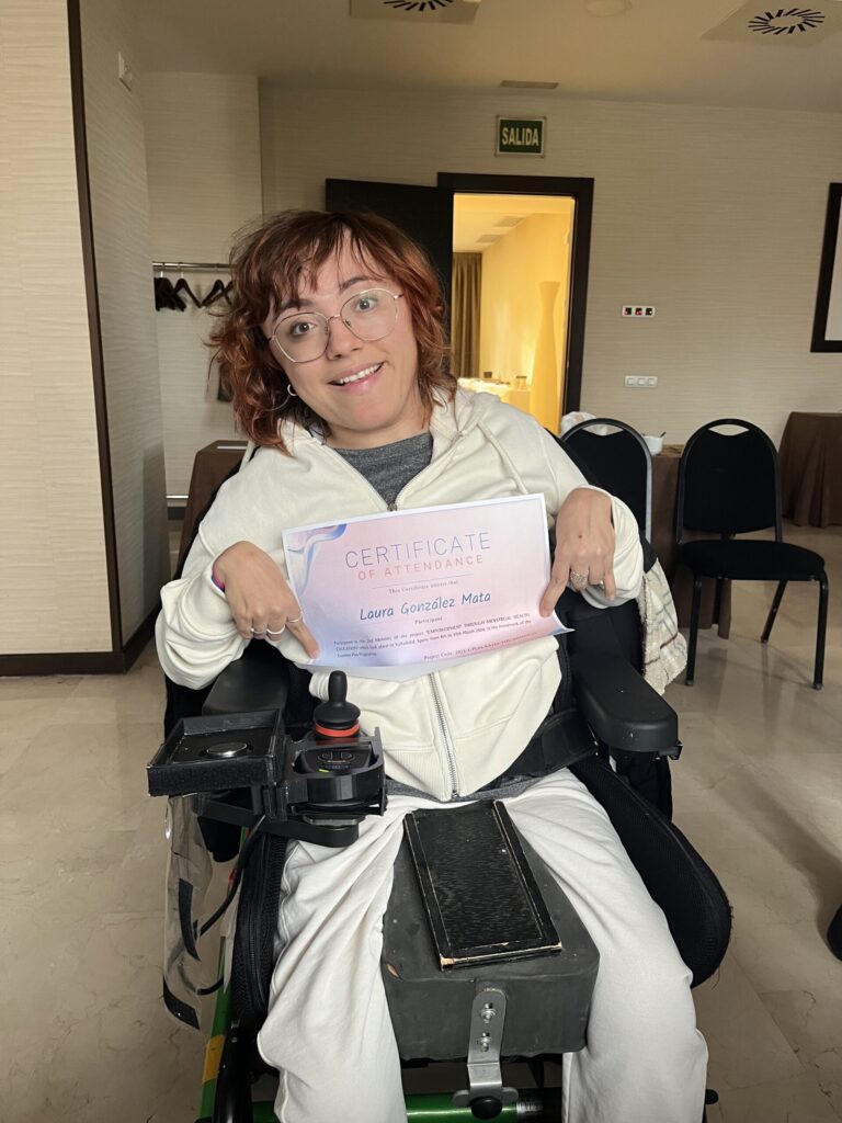 Una mujer con parálisis cerebral sostiene un diploma con su nombre.