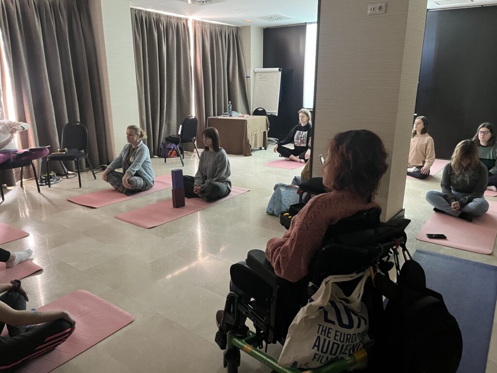 Un grupo de personas, entre ellas una mujer con parálisis cerebral, practican yoga.